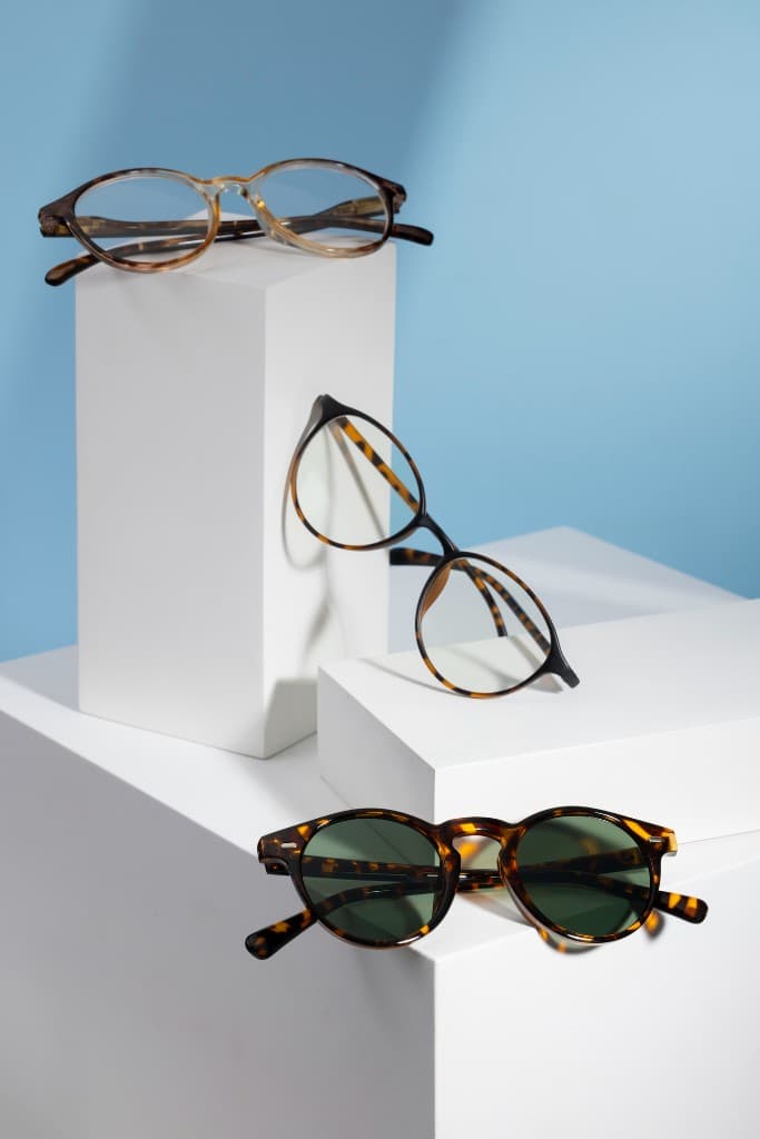 Three pairs of eyeglasses displayed on white geometric blocks