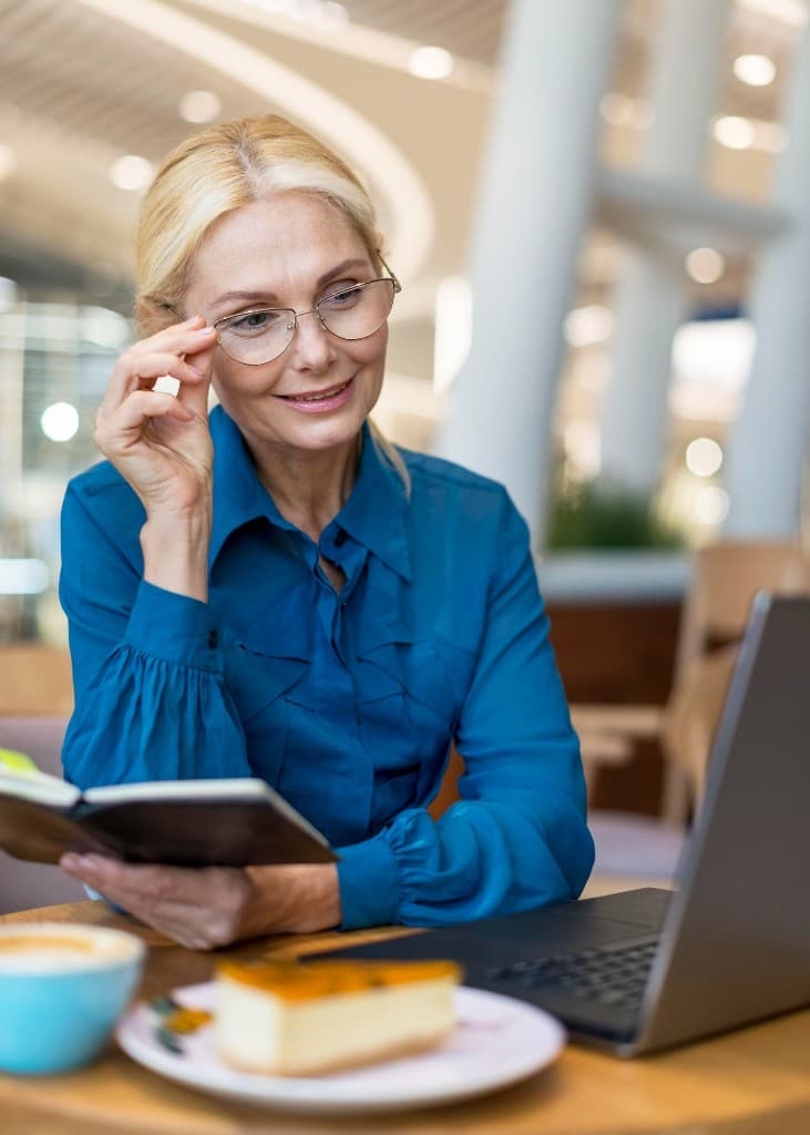 Woman wearing glasses while working on a laptop in a cafe