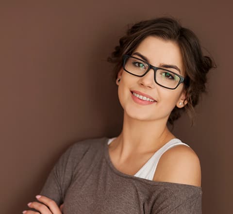 Woman wearing black rectangular glasses and a warm off-shoulder top