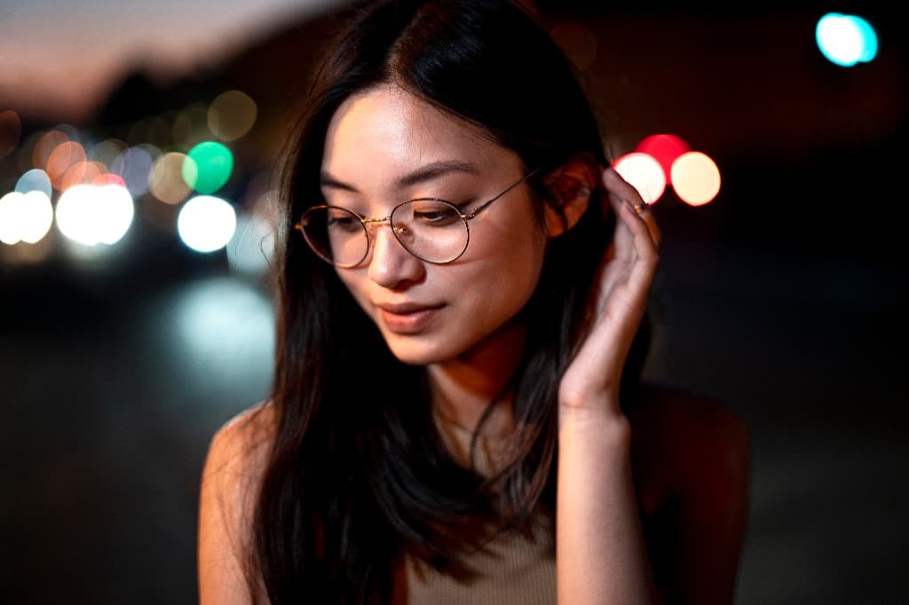 Woman wearing thin gold-rimmed round glasses at night