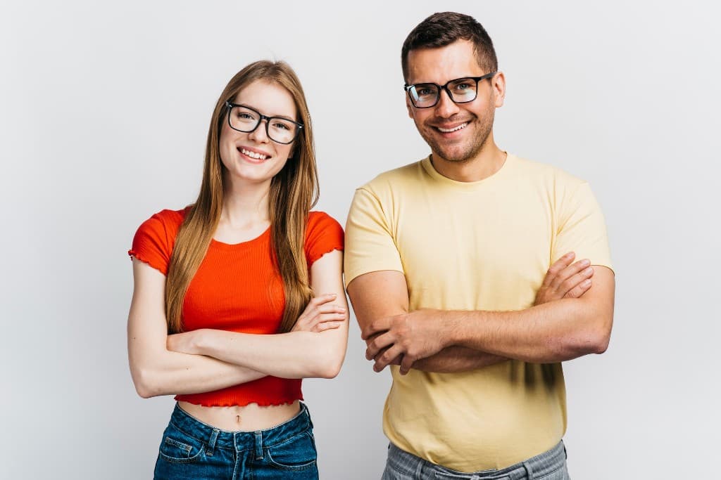 Smiling man and woman wearing black-rimmed eyeglasses